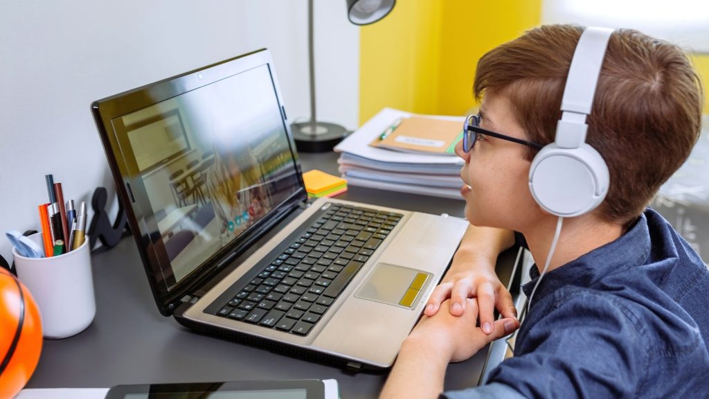 Dete uči srpski jezik putem onlajn časa, koristeći interaktivne materijale na ekranu laptopa.